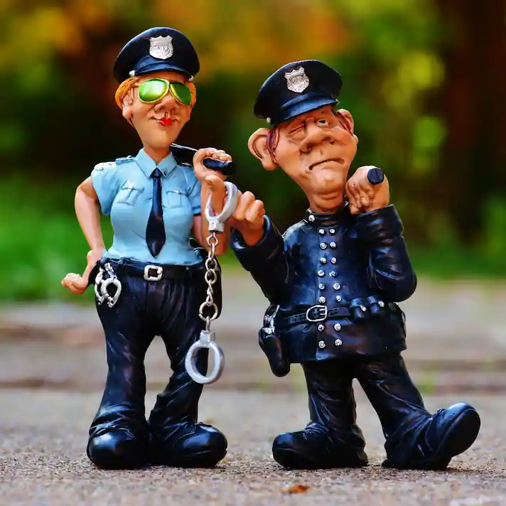 Abogado especialista en atentado, resistencia y desobediencia en Valladolid | Defensa con estrategia Figuras caricaturescas de dos policías con esposas y actitud vigilante, representando situaciones legales relacionadas con autoridad y detención.
