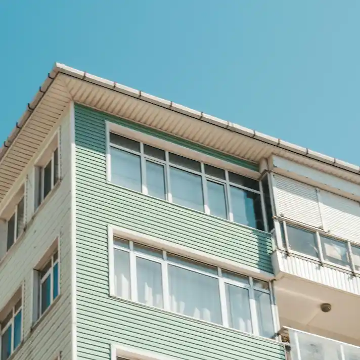 Fachada de edificio residencial iluminado por el sol, representando propiedades sujetas a IBI y Plusvalía en Valladolid.