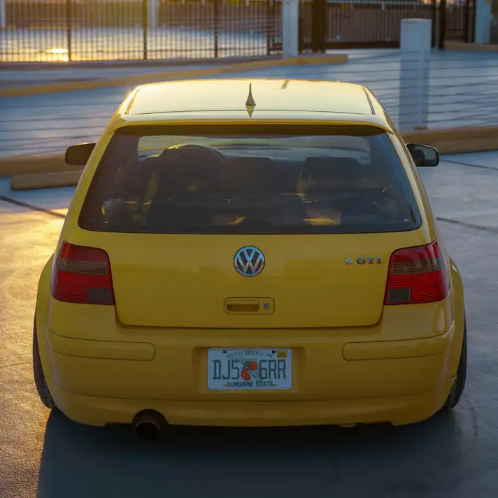 Coche amarillo detenido con matrícula visible al atardecer, simbolizando un posible delito contra la seguridad del tráfico.